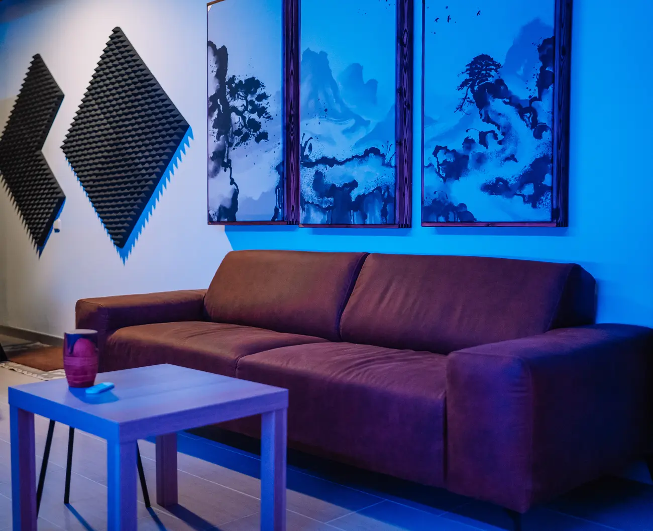 The lounge with a leather couch under three ink-art acoustic panels