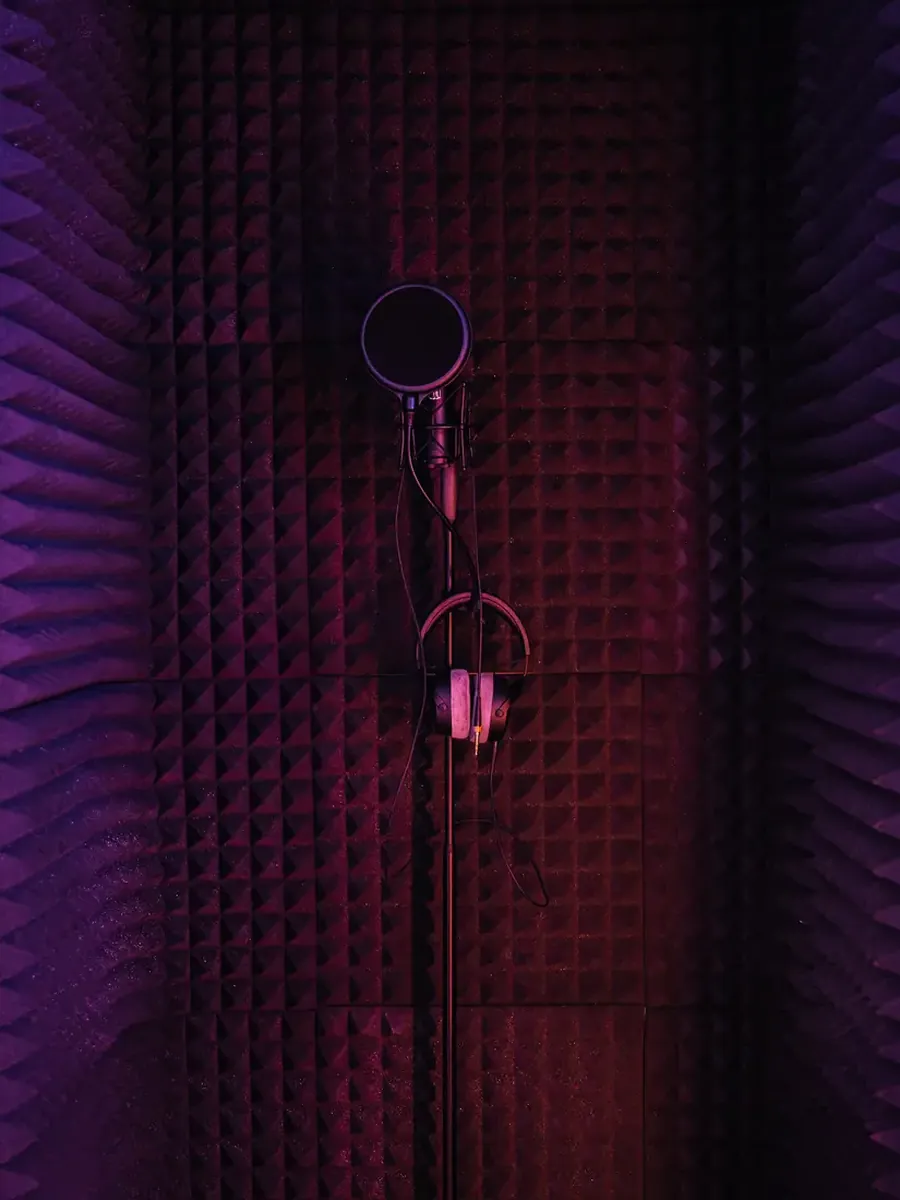 The vocal booth lined with acoustic foam, a microphone with pop filter and headphones